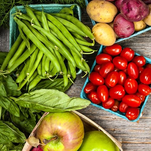 Apples, tomatoes, peas, potatoes, and basil on a table